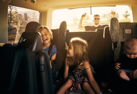 Dad Loading Car While Kids Play in Backseat