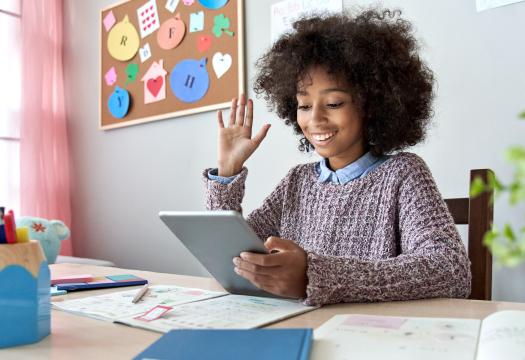 Girl raising her hand while on a video call for school.