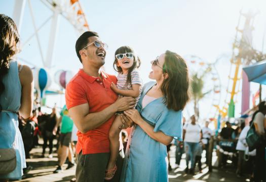 A cute mixed race family enjoys the rides and sun at the fair activities on Santa Monica Pier | Merry Maids