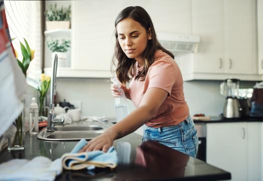 Young woman cleaning the countertops in her kitchen. | Merry Maids®