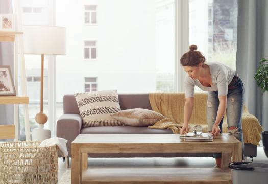 Young woman cleaning and organizing her living room space. | Merry Maids®