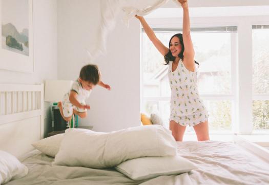 Mother and child play on freshly-made white bed