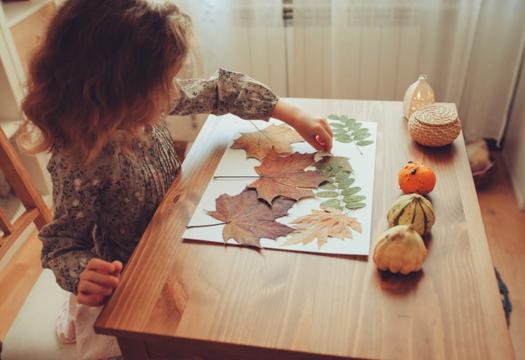 Little girl creating leave collage at desk | Merry Maids