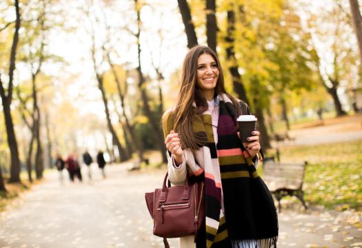 Pretty young woman with coffee cup in the autumn park | Merry Maids